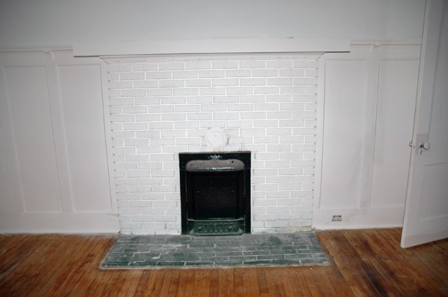 Coal fire place surrounded by the painted wooden wainscoting.